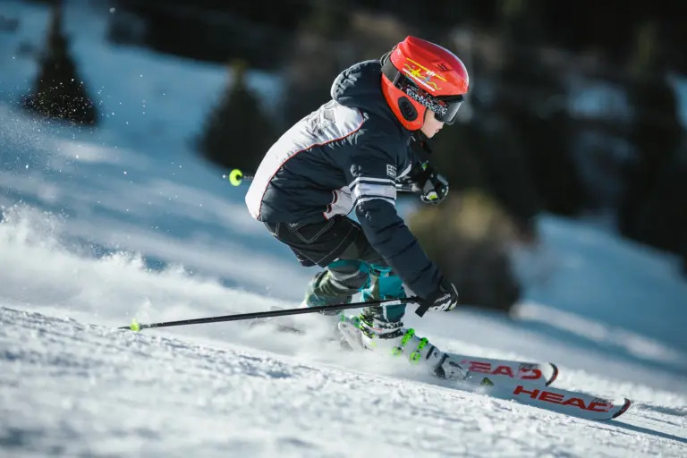 A skilled skier descending a slope swiftly, wearing ski boots, a helmet, and holding ski poles