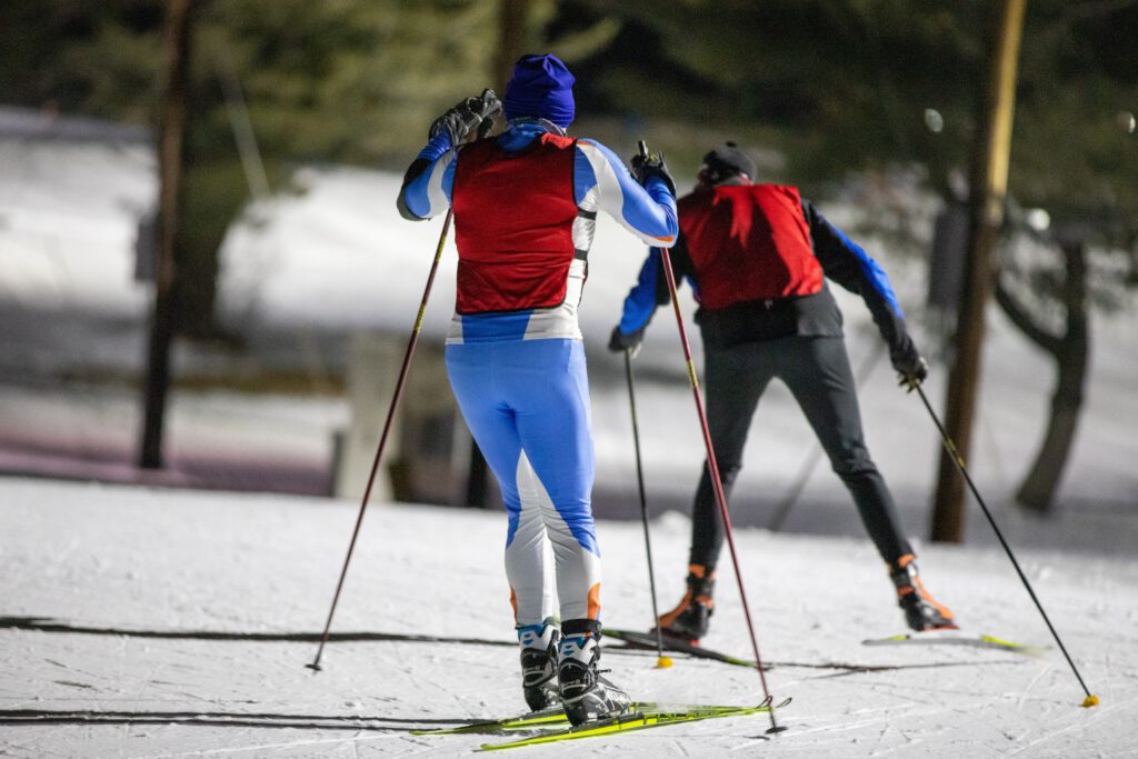 Skiers engaged in the skating technique, showcasing the use of longer cross-country ski poles.