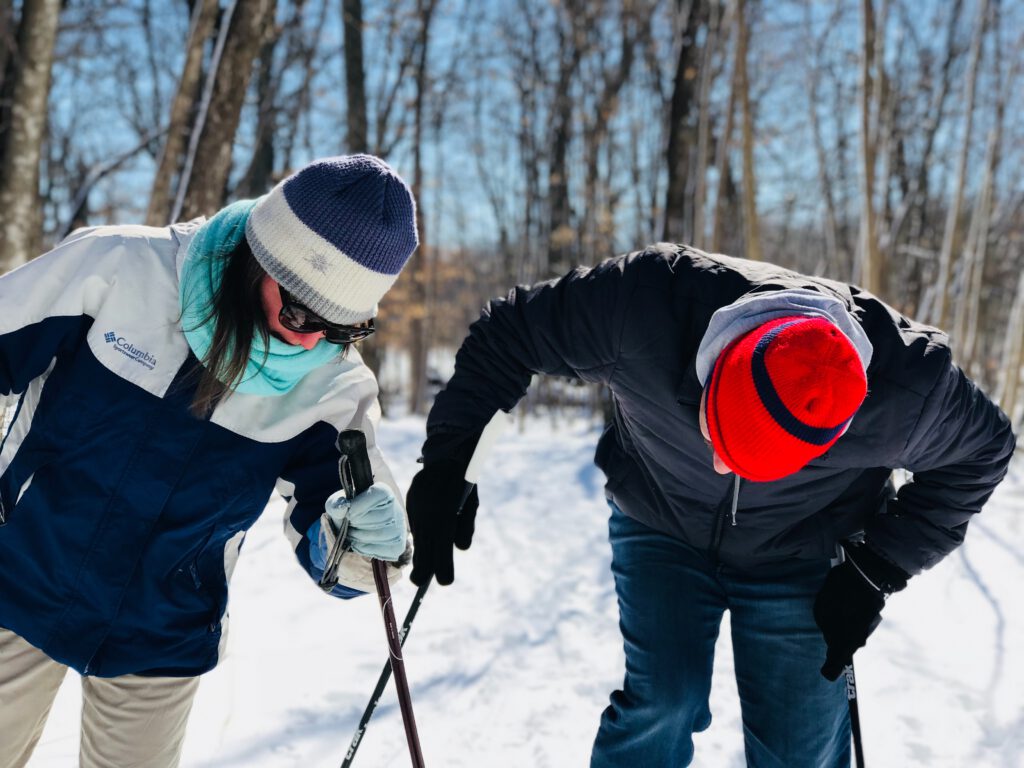 A couple inspecting their ski poles to ensure proper height alignment.